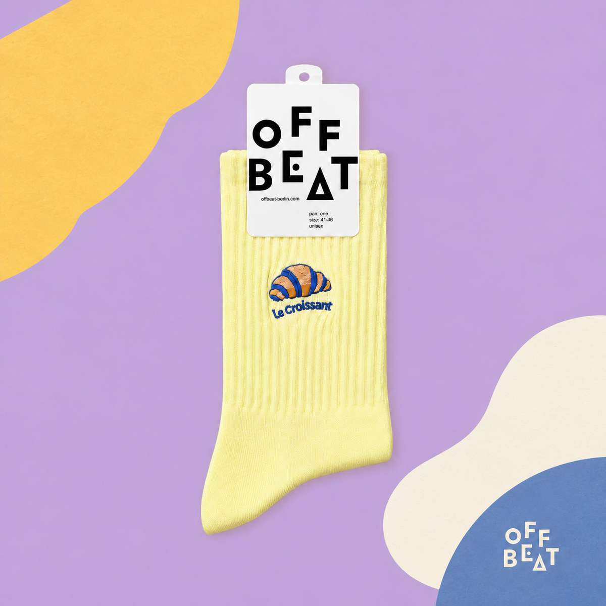 Yellow embroidered croissant socks on an abstract lavender, yellow and blue background